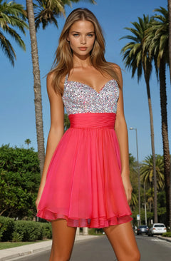 A woman stands outdoors beneath palm trees and a blue sky, wearing the La Femme Short Tiered Party Dress with Beads in pink and silver, featuring a beaded sweetheart bodice.