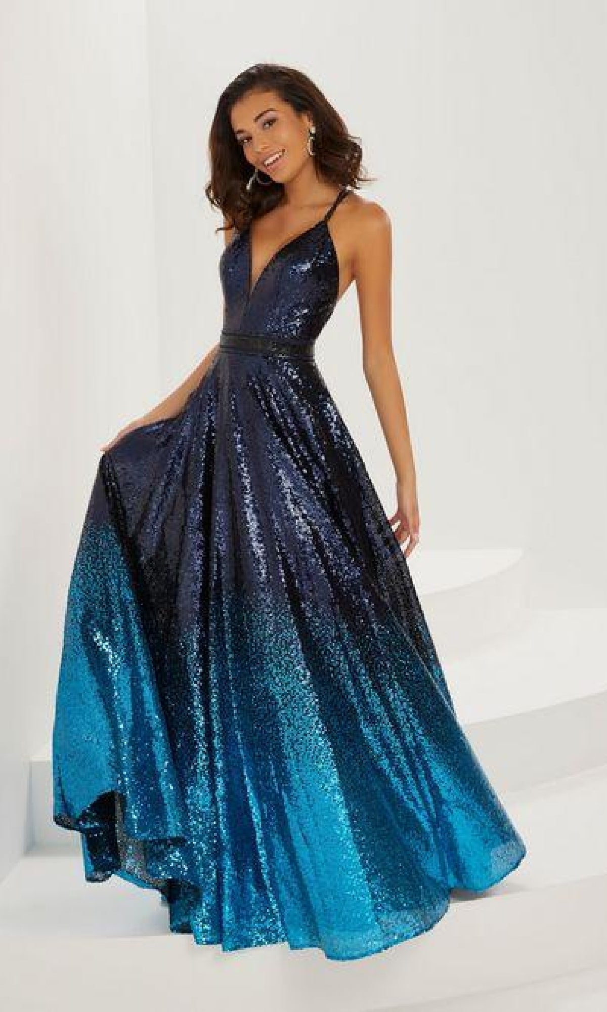 A woman wears the A-Line Sequin Ombre Prom Dress: Tiffany 16941, featuring a sleeveless design, floor-length a-line skirt, and low V-neckline, shown against a plain white background.