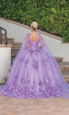 Wearing the Quinceanera Dress 1695 By Dancing Queen, a person in an a-line gown with floral details and sheer cape sleeves stands on a patio facing away, steps and greenery behind them.