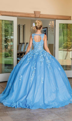 A woman outdoors faces glass doors in the Quinceanera Dress 1707 By Dancing Queen, a blue ball gown featuring a full skirt, lace-up back, and floral embroidered lace.