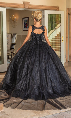 A person stands indoors facing away, wearing the floor-length black Quinceanera Dress 1707 By Dancing Queen featuring a cutout and floral embroidered back. Double doors and a staircase are visible in the background.