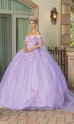 A woman wears the Quinceanera Dress 1714 By Dancing Queen, a lilac A-line gown with floral details and a crown, standing outside a building with large windows and stone columns.