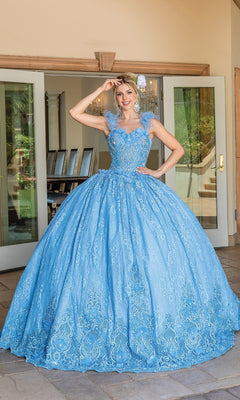 A woman stands outside in front of glass doors wearing Quinceanera Dress 1721 By Dancing Queen, featuring a light blue ball gown with a full skirt, floral lace details, and a romantic sweetheart neckline.