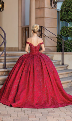 A woman stands with her back to the camera in front of stone steps and a building, wearing the Burgundy Red Quinceanera Dress 1722—an off-the-shoulder ball gown featuring a full skirt.