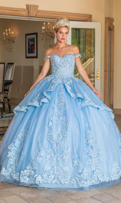 Wearing the Quinceanera Dress 1741 By Dancing Queen, a woman with a tiara stands before open doors in a formal room, showcasing the ornate ball gown's off-the-shoulder straps and intricate embroidery.