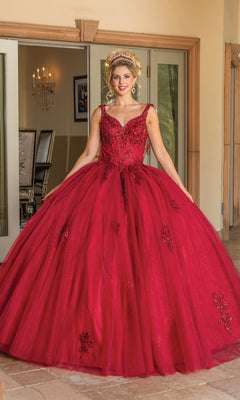 A woman stands indoors in the Quinceanera Dress 1767 By Dancing Queen, a red, floor-length ball gown with lace and sequin details and a sweetheart neckline. She wears a matching tiara; glass doors and a chandelier are in the background.