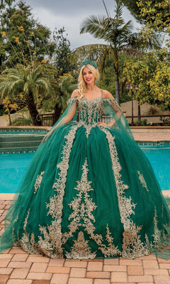 A person stands by a pool in the Quinceanera Dress 1768 By Dancing Queen, featuring gold embroidery and sheer cape sleeves, with palm trees and lush greenery as a stunning backdrop.