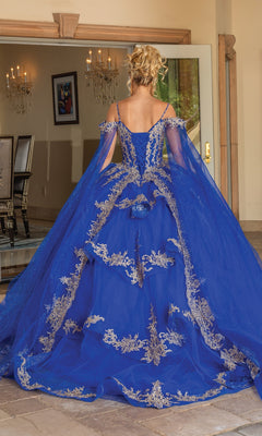 A woman with blond hair in an updo wears the Quinceanera Dress 1768 by Dancing Queen, featuring ornate gold embroidery and cape sleeves, as she stands with her back to the camera in an elegant room.