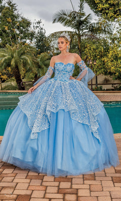 By the pool, a woman wearing the Quinceanera Dress 1773 By Dancing Queen—with lace, floral details, removable sheer sleeves, and a tiara—stands surrounded by lush greenery.
