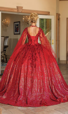 A person wearing the Quinceanera Dress 1776 By Dancing Queen, a sparkling red A-line gown with sheer long sleeves, stands indoors facing away from the camera.