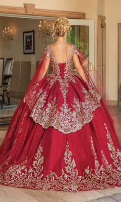 Indoors, a woman faces away from the camera wearing the Quinceanera Dress 1781 By Dancing Queen—a burgundy gown with gold embroidery and a flowing train.