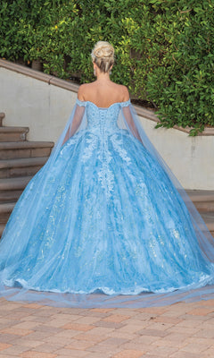 A woman with blonde hair in an updo wears the Quinceanera Dress 1782 By Dancing Queen, a light blue off-the-shoulder gown with lace, tulle details, and a sweetheart neckline, standing outdoors with her back to the camera.