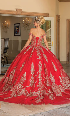 A woman models the Quinceanera Dress 1783 By Dancing Queen, featuring an off-the-shoulder design with gold lace embroidery, standing in a formal setting and showcasing its full, ornate skirt and train.