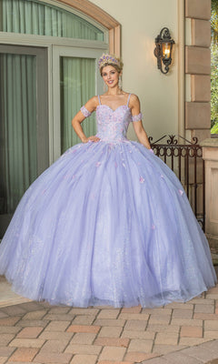 A young woman in the Quinceanera Dress 1785 By Dancing Queen, featuring a glittery lilac ball gown and sweetheart neckline, with matching arm cuffs and a tiara, stands outside near stone columns and a wrought iron railing.
