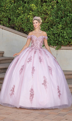 A woman in the Quinceanera Dress 1797 By Dancing Queen, featuring off the shoulder lace applique and floral details, stands on a stone pathway outdoors wearing a tiara, with lush greenery in the background.