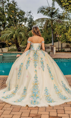 A woman wearing the Quinceanera Dress 1823 By Dancing Queen, featuring blue floral embroidery and an off-the-shoulder design, stands by a swimming pool facing away from the camera.