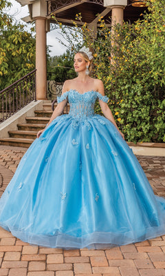 A woman in the Quinceanera Dress 1826 By Dancing Queen, an off-shoulder light blue gown with floral lace appliques and a tiara, stands on a brick path near greenery and stairs for an elegant look.