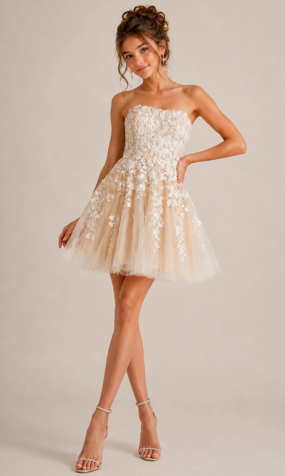 A woman wearing the Short Homecoming Dress: Jovani 1830, a strapless fit-and-flare design with white floral lace appliques and a tulle skirt, stands on one leg with her hand on her hip.