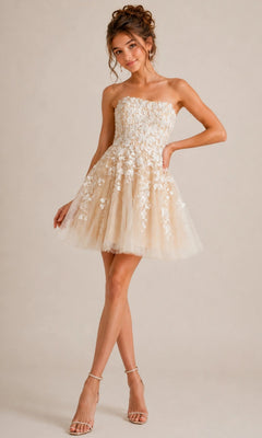 A woman wearing the Short Homecoming Dress: Jovani 1830, a strapless fit-and-flare design with white floral lace appliques and a tulle skirt, stands on one leg with her hand on her hip.