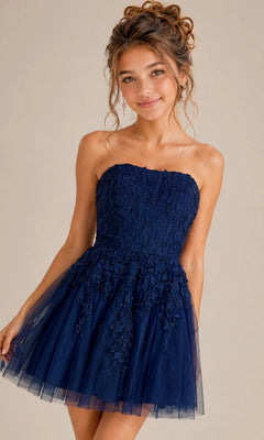 A woman stands against a plain background and smiles, wearing the Short Homecoming Dress: Jovani 1830— a strapless fit-and-flare dress adorned with intricate floral lace appliques and featuring a navy blue tulle skirt.