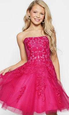 A girl wearing the Jovani 1830 short homecoming dress in hot pink, which features a strapless fit-and-flare design with floral lace appliques and a tulle skirt, smiles at the camera.