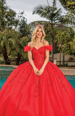 A woman wearing the Quinceanera Dress 1834 By Dancing Queen and a tiara stands in front of a pool, surrounded by palm trees and lush greenery.