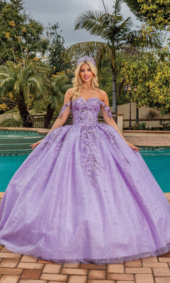 A woman stands by a pool surrounded by palm trees, wearing the Quinceanera Dress 1862 By Dancing Queen—an off-the-shoulder ball gown with floral embellishments and a sweetheart neckline.