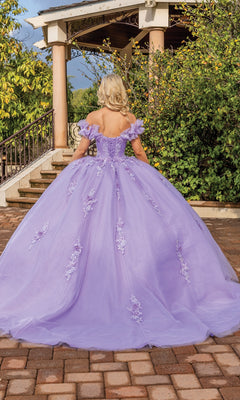 A woman in the Quinceanera Dress 1870 By Dancing Queen, featuring a lilac off-the-shoulder ball gown and sweetheart neckline, stands on a brick path with a gazebo and lush greenery in the background.