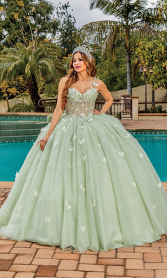A woman wearing the Quinceanera Dress 1879 by Dancing Queen—a light green ball gown with floral details and a tiara—smiles as she stands by a swimming pool.