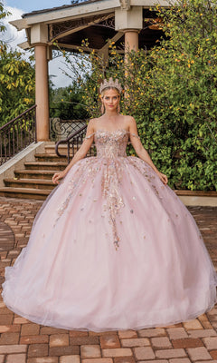 A woman poses outdoors in front of stone steps and greenery, wearing the Quinceanera Dress 1894 By Dancing Queen—an a-line pink ball gown with floral accents, jeweled crown, and sweetheart neckline.