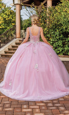Someone stands outdoors facing away from the camera, wearing the Quinceanera Dress 1896 By Dancing Queen—a blush pink gown with floral embellishments, lace embroidery, and a lace-up back.