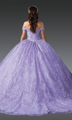 A woman with long, wavy hair is seen from behind against a gray background, wearing the Quinceanera Dress 1901 by Dancing Queen—an off-the-shoulder gown in soft lavender with a full, sparkling skirt and an ornate headpiece.