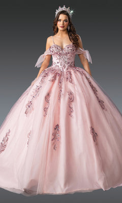 A woman wearing the Quinceanera Dress 1902 by Dancing Queen in blush, featuring a tulle ballgown skirt with sequin embellishments and an embellished bodice, paired with a matching tiara, stands against a plain gray background.