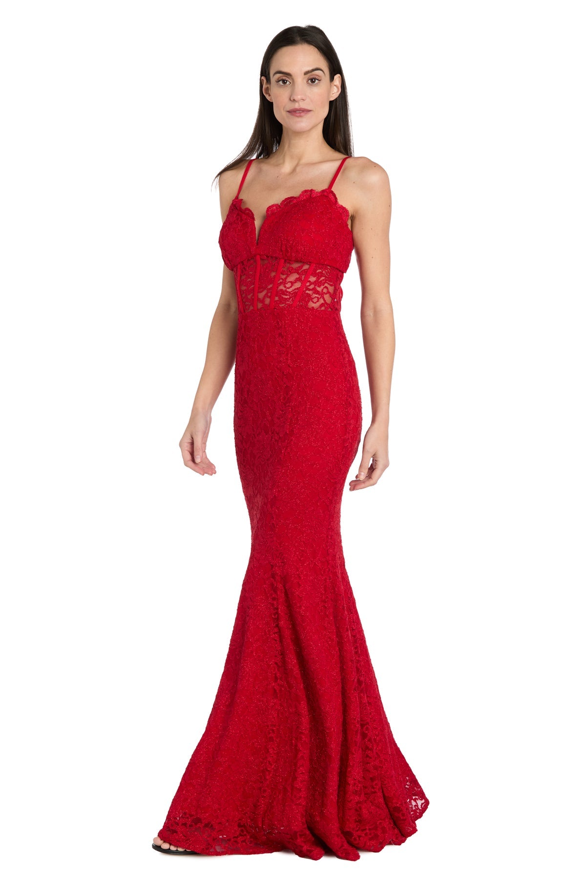 A woman models the Morgan 19069 long red lace prom dress, a floor-length, form-fitting gown with thin straps and a sheer lace midsection, standing against a plain white background. This elegant mermaid style highlights her silhouette.