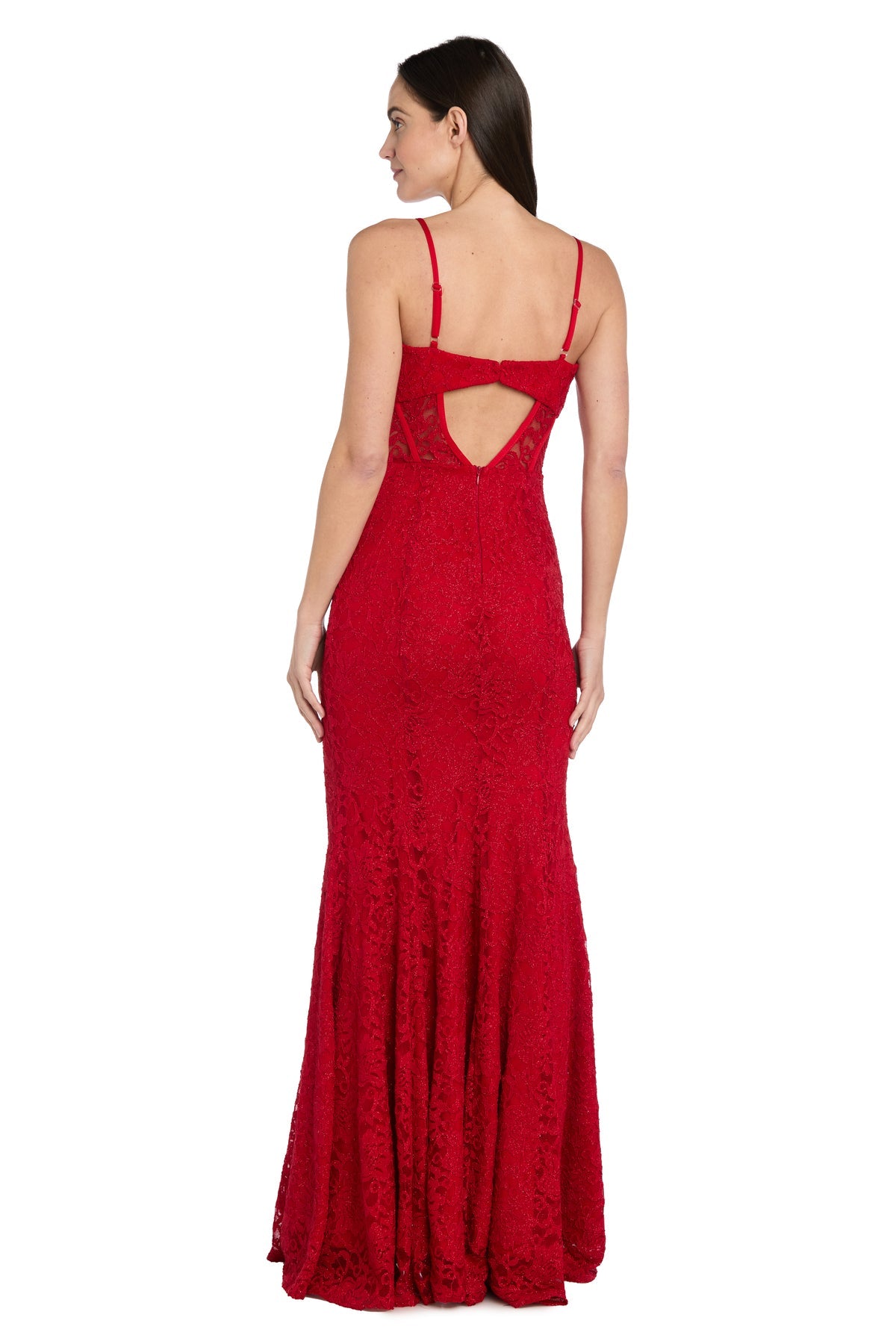 A woman stands facing away, wearing the Morgan 19069— a long red lace prom dress with spaghetti straps, an open back, and a cut-out detail.
