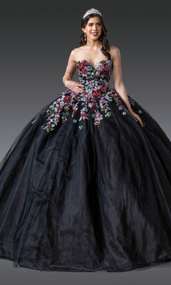 A woman wears the Black Quinceanera Dress 1927 By Dancing Queen, featuring colorful floral embroidery and glitter tulle, standing against a plain gray background with a sparkling tiara completing her look.