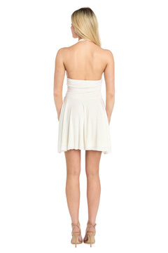 A woman stands with her back to the camera, wearing the Morgan 19282 short homecoming dress—a strapless white fit-and-flare style—paired with beige heels, against a plain white background.