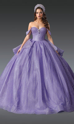 A woman wearing the Quinceanera Dress 1937 By Dancing Queen, a sparkling lavender ball gown with off-the-shoulder straps and a full skirt, plus a tiara, stands against a plain gray background.