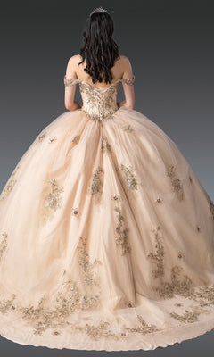 A woman wearing the Quinceanera Dress 1943 by Dancing Queen, featuring glitter tulle and gold floral embroidery with a tiara, stands facing away against a gradient gray background.