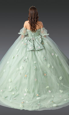 A woman wears the Quinceanera Dress 1945 by Dancing Queen in sage green, featuring 3D flowers, a large bow, an off-the-shoulder neckline, and a voluminous ball gown skirt as she stands facing away.