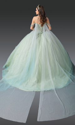 A woman with long brown hair wears the Light Green Quinceanera Dress 1950 By Dancing Queen, featuring a beaded corset bodice, off-shoulder straps, and a sheer train, standing against a plain gray backdrop.