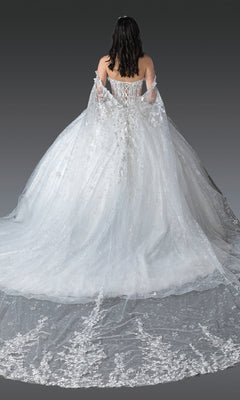 A woman with dark hair, seen from behind, wears the Quinceanera Dress 1970 by Dancing Queen—an elegant white gown featuring a long lace train, off-the-shoulder sleeves, and delicate 3D floral embellishments.