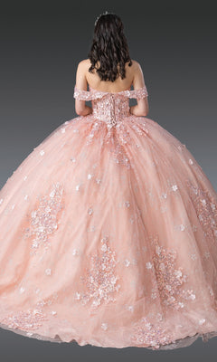 A woman in the Quinceanera Dress 1971 by Dancing Queen, featuring blush pink fabric and 3D flower embellishments, stands facing away to display the gown’s full skirt and elegant lace-up back.