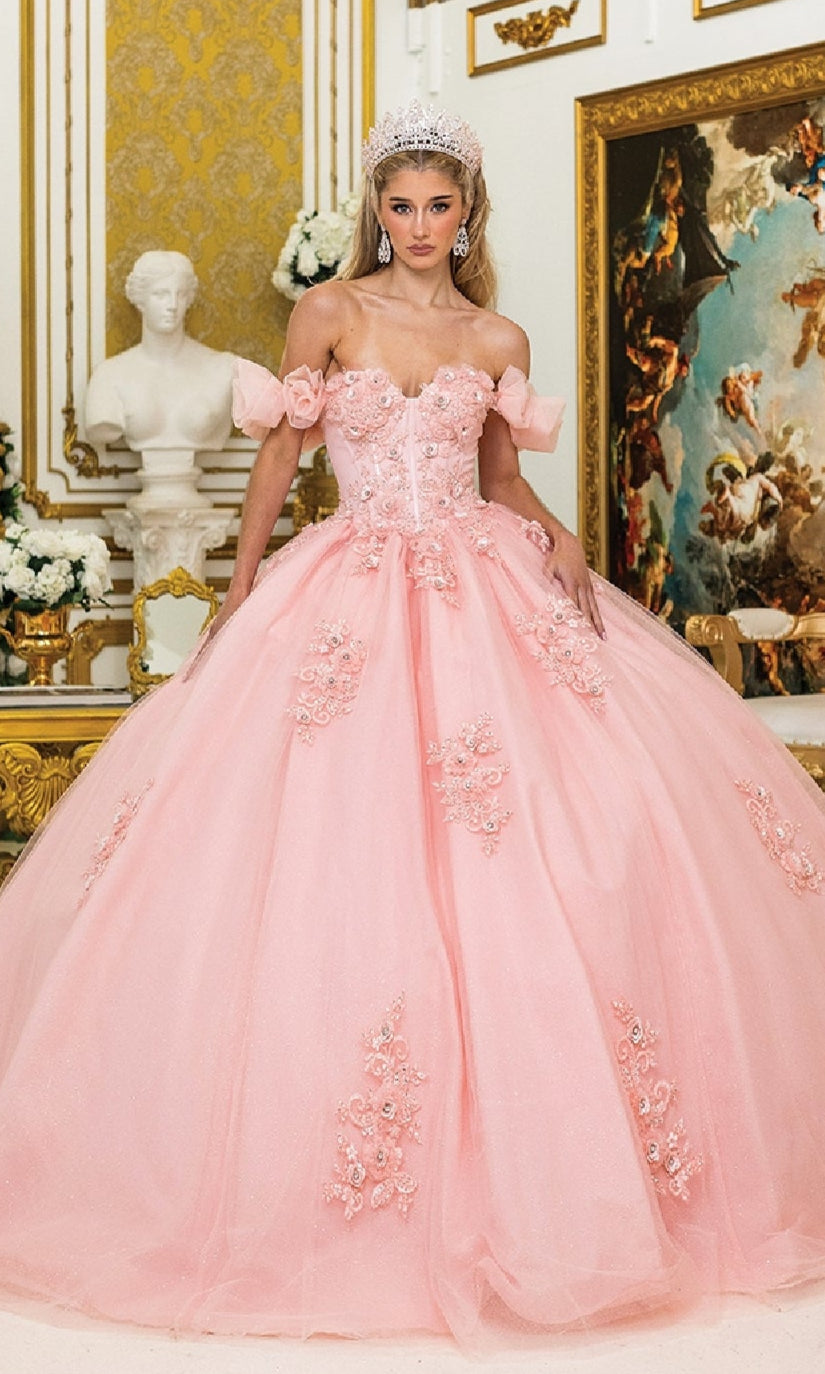 A woman wearing the Quinceanera Dress 1976 By Dancing Queen, featuring floral details and a corset bodice, stands in an ornate, gold-accented room decorated with classical art and sculptures.