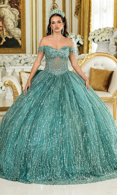 A woman wears the Long Corset Quinceañera Dress: Dancing Queen 1982, featuring an ornate off-the-shoulder design and a full, sequin-embellished skirt, standing in an elegant room with gold accents.