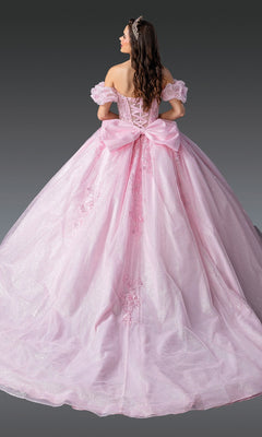 A woman in the Quinceanera Dress 1985 By Dancing Queen, a sparkling pink ball gown with floral details, a large bow, lace-up corset bodice, and long full skirt, stands facing away to showcase its elegant back design.