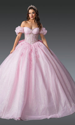 A woman in the Quinceanera Dress 1985 By Dancing Queen, featuring a sparkling pink ball gown with a lace embroidered corset bodice and off-the-shoulder sleeves, poses with a tiara against a neutral gray background.