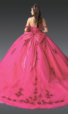 A woman wearing the Quinceanera Dress 1986 by Dancing Queen, featuring a bright pink hue, corset bodice, off-the-shoulder sleeves, sequin embellishments, and a large back bow, stands against a dark background.