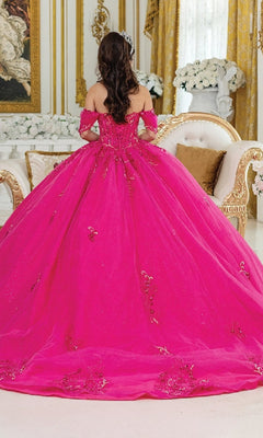 A woman with long brown hair, seen from behind, sits on an ornate cream and gold sofa in an elegant room wearing the Pink Quinceanera Dress 1987 By Dancing Queen, featuring fuchsia pink fabric with gold details and a corset bodice.