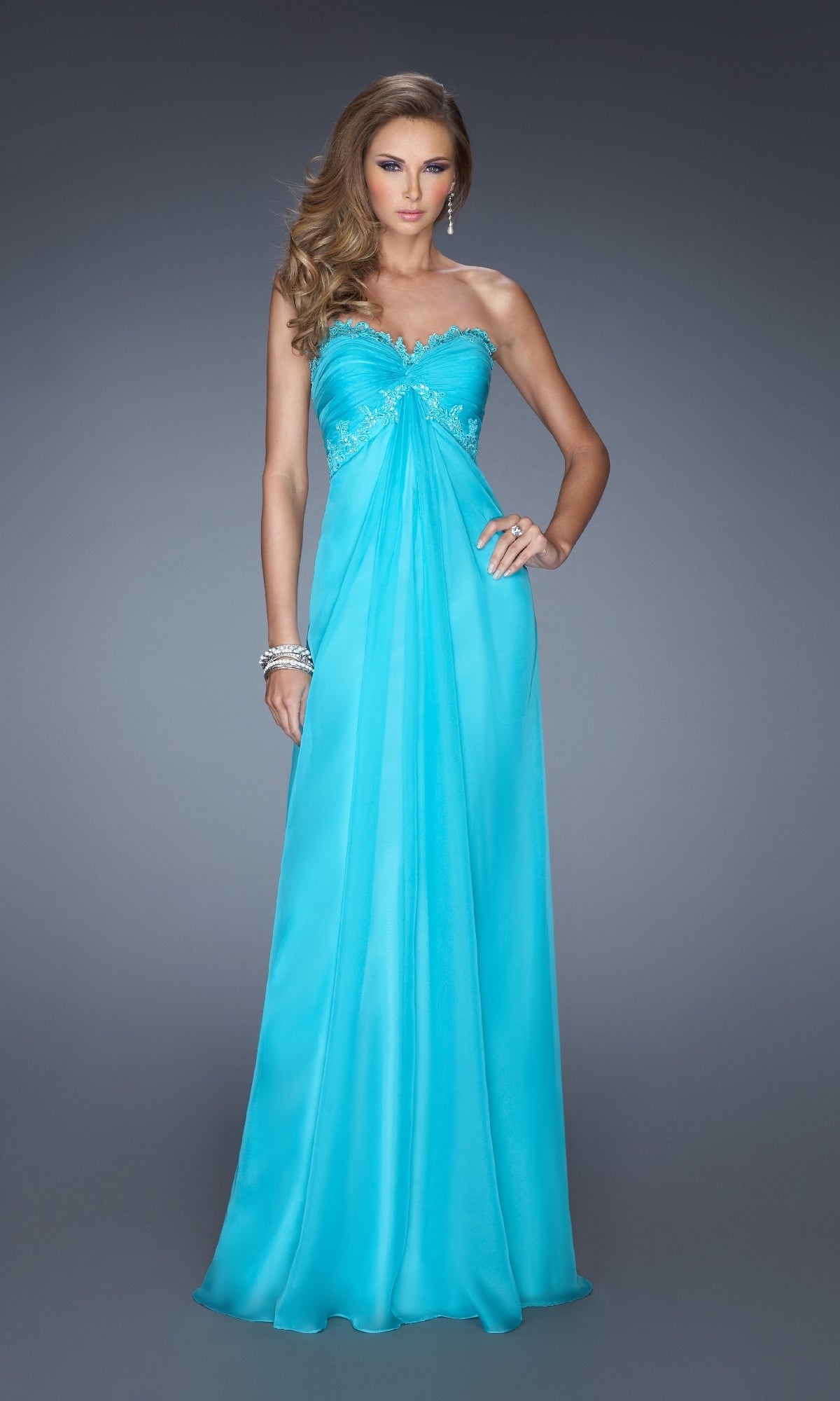 A woman models the Strapless Long A-Line Prom Dress: La Femme 20042 in turquoise with silver embellishments, standing against a plain grey background.